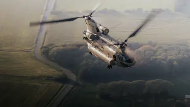 Een grote grijze helikopter vliegt onder een bewolkte lucht.