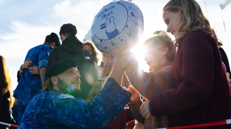 Mensen knuffelen elkaar na de aankomst van een marineschip.