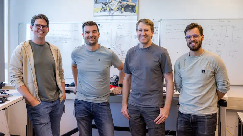 4 jongemannen poseren in een werkruimte voor flipovers