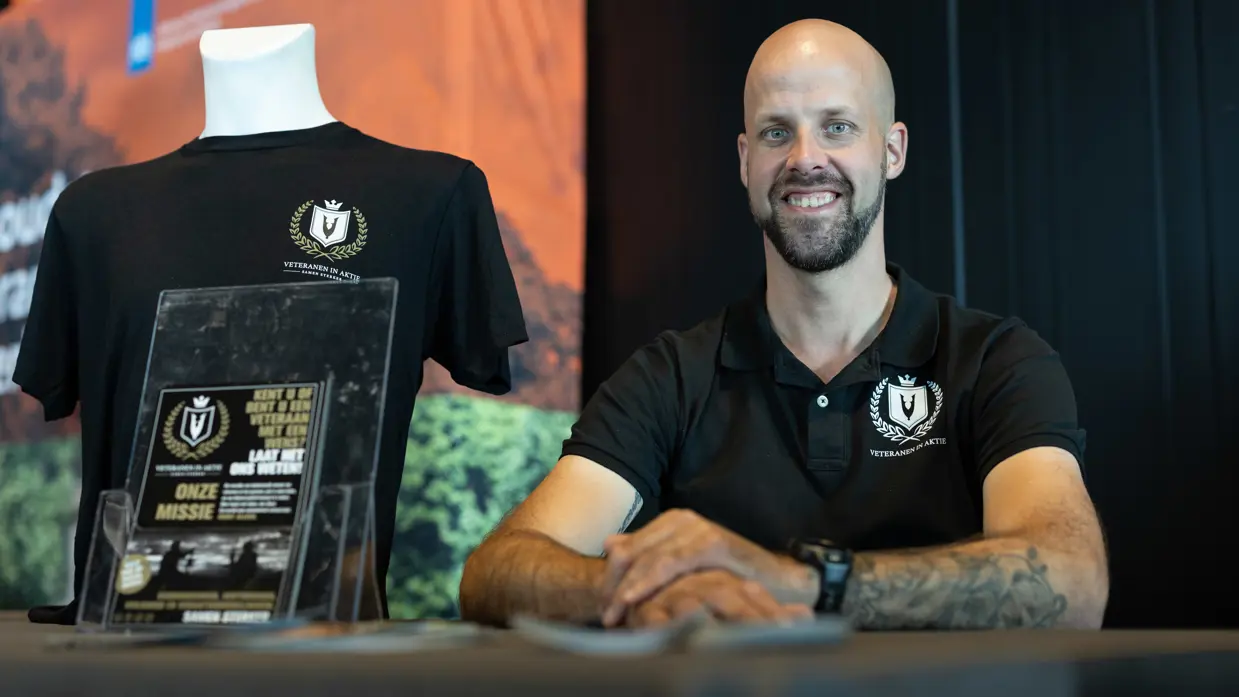 Jordy Hilt poseert achter een tafel waarop Veteranen in Aktie-spullen liggen.