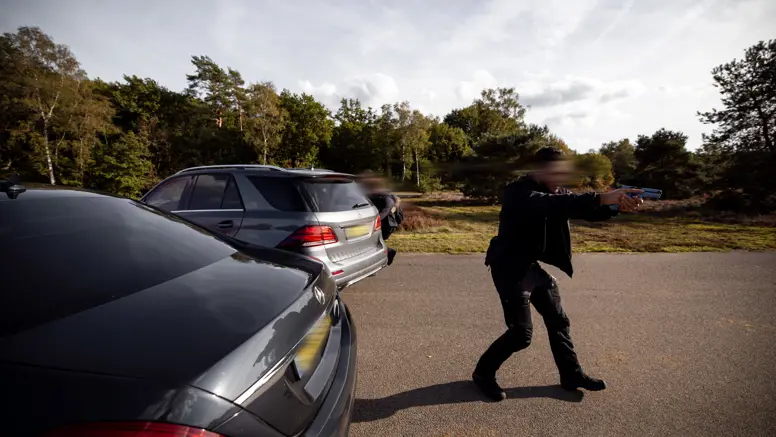 Een militair van de PBB die in een actieve houding met een wapen dekking geeft nabij voertuigen tijdens een oefening op de Vlasakkers.