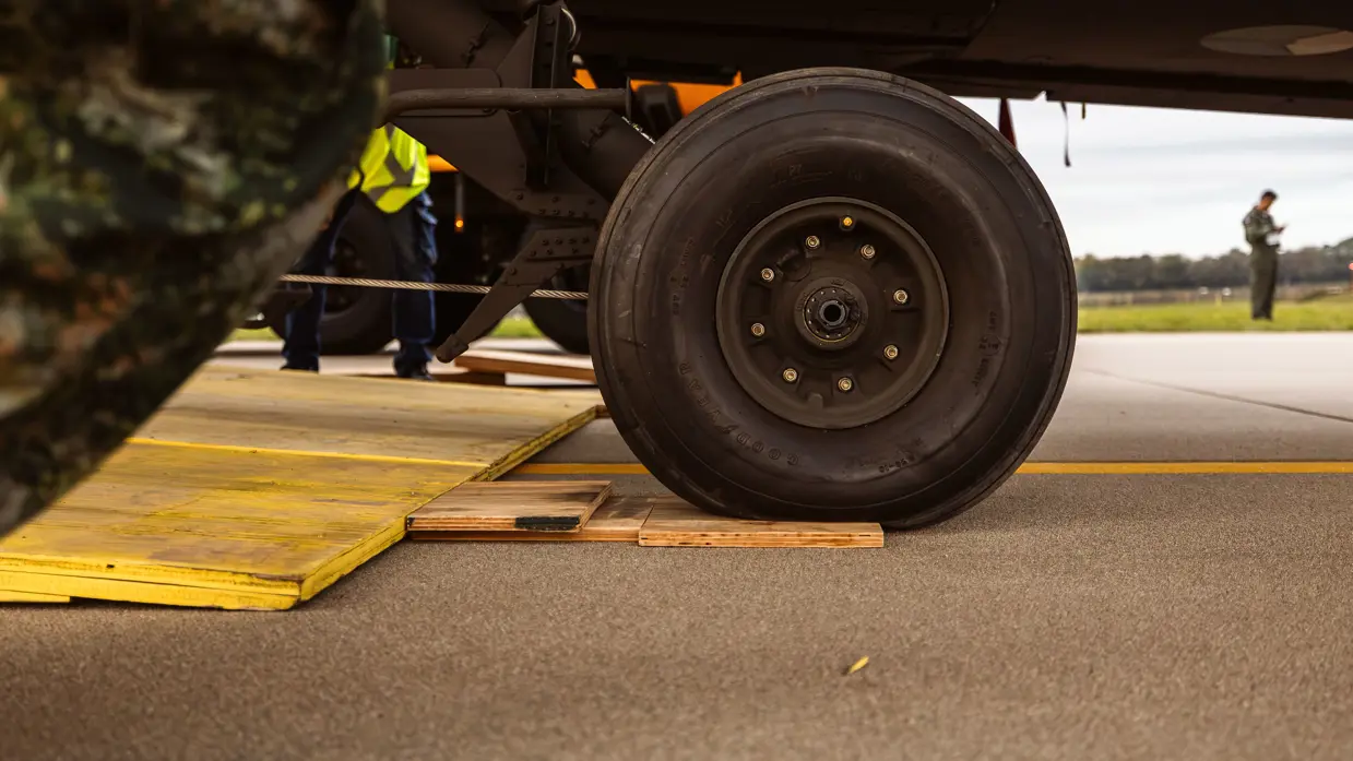 Close-up van een wiel van het landingsgestel dat van de laadklep rolt.