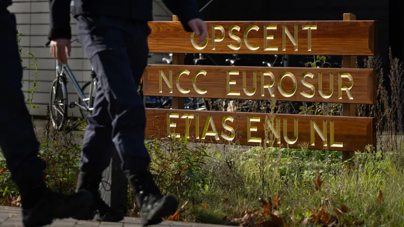 Bord van het OPSCENT waar twee marechaussees voor langs lopen.