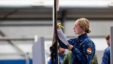 Een vrouwelijke militair tekent iets op een bord