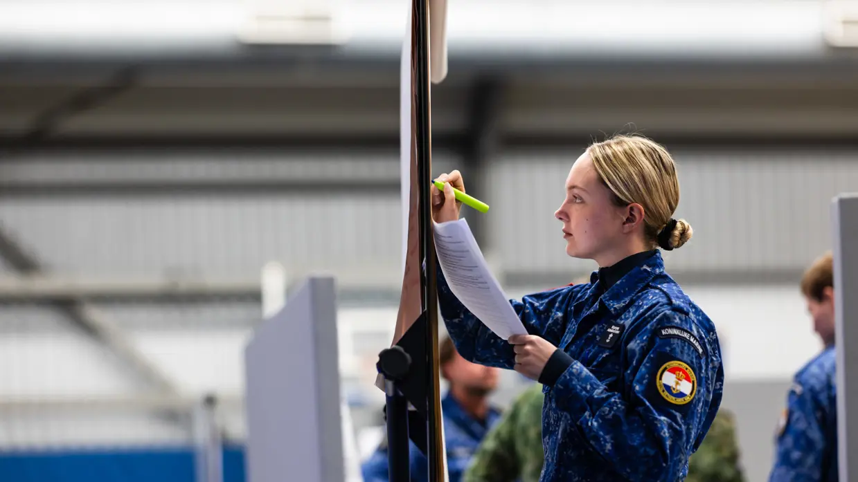 Een vrouwelijke militair tekent iets op een bord