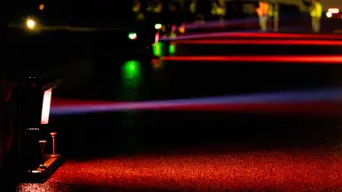De lichten trekken rood en groene kleurstrepen over het asfalt.&nbsp;
