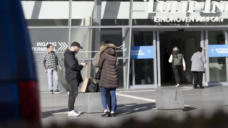 Agenten in burger in gesprek met een vrouw op Eindhoven Airport.