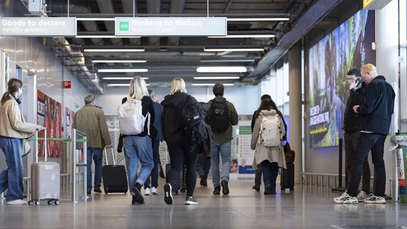 Reizigers op Eindhoven Airport, op de rug gezien.