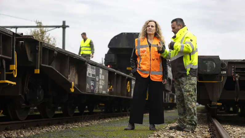 Een vrouw en een man bij een trein die wordt beladen me militair materieel. 