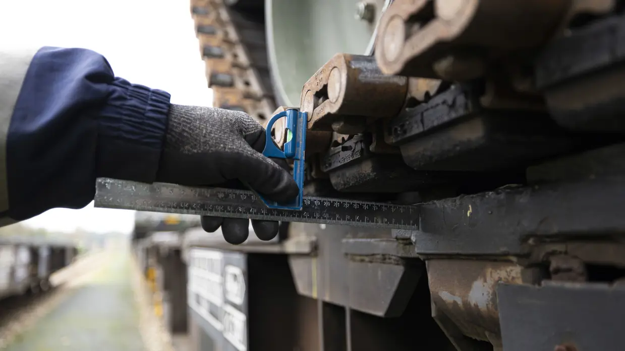 Een hand en een liniaal aan de zijkant van een beladen trein.