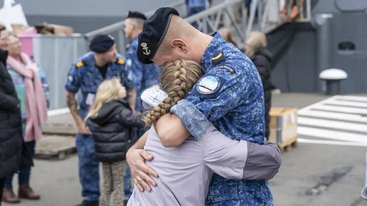 Een marineman knuffelt een meisje.