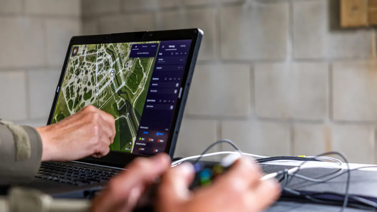 Syl en Lucas kijken naar een scherm, handen op het bedieningsbakje en handen op de laptop    