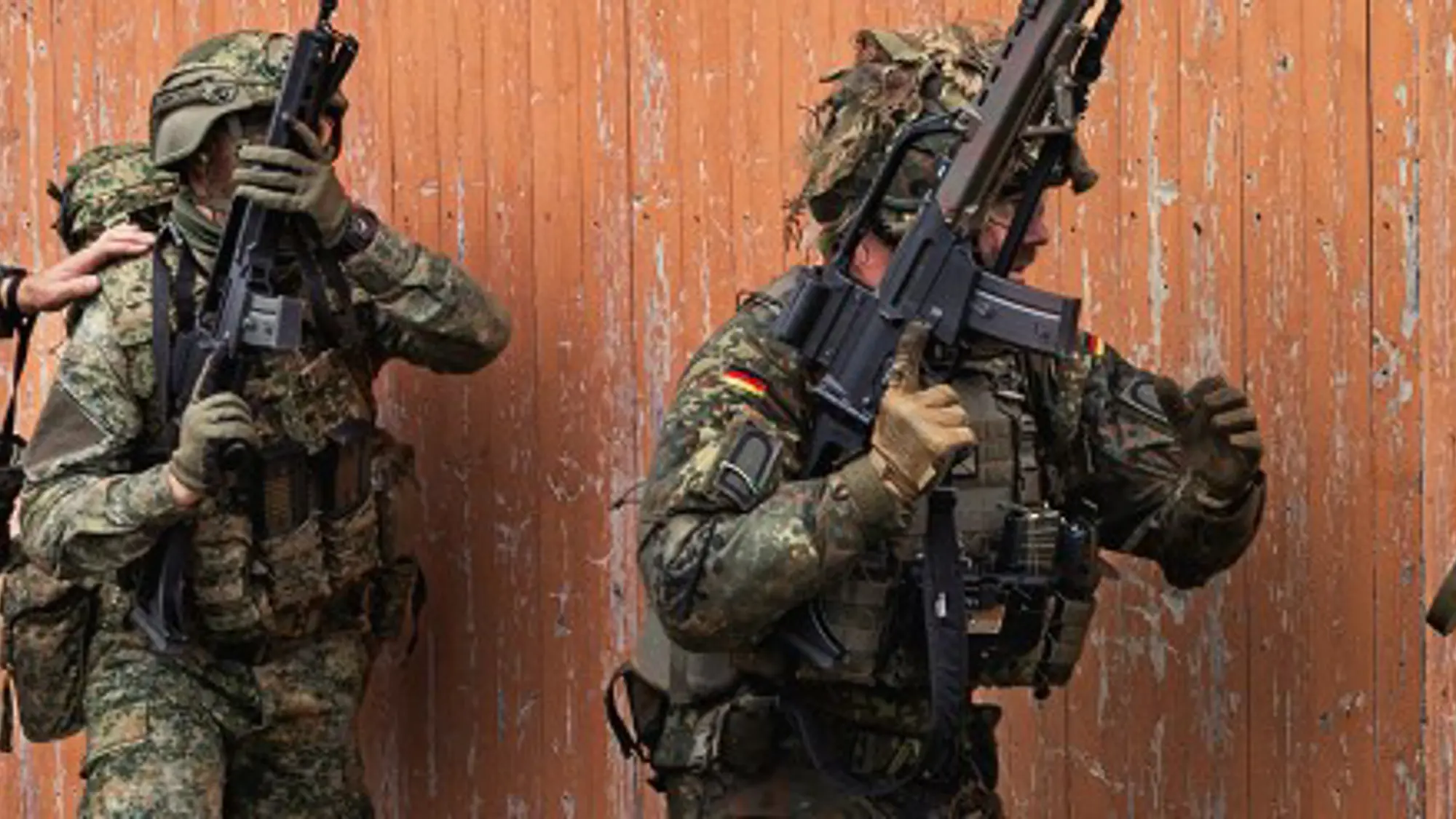 Militairen met wapens in de aanslag bewegen zich rondom een gebouw.