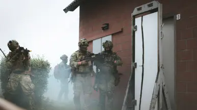 Een aantal zwaarbewapende militairen gaan schietend een huis binnen.