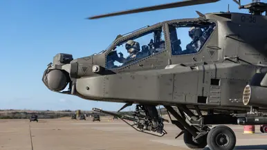 Twee vliegers in de cockpit van een Apache op een platform.