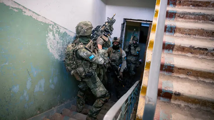 Militairen met getrokken geweren in een oud trappenhuis.