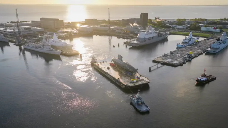 De versleten onderzeeboot Walrus vaart op een ponton de marinehaven in Den Helder uit.