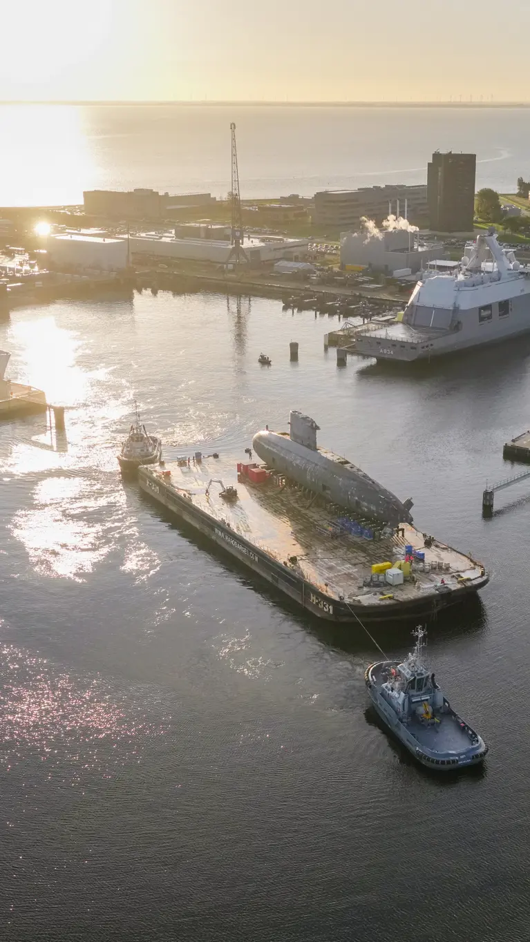 De versleten onderzeeboot Walrus vaart op een ponton de marinehaven in Den Helder uit.