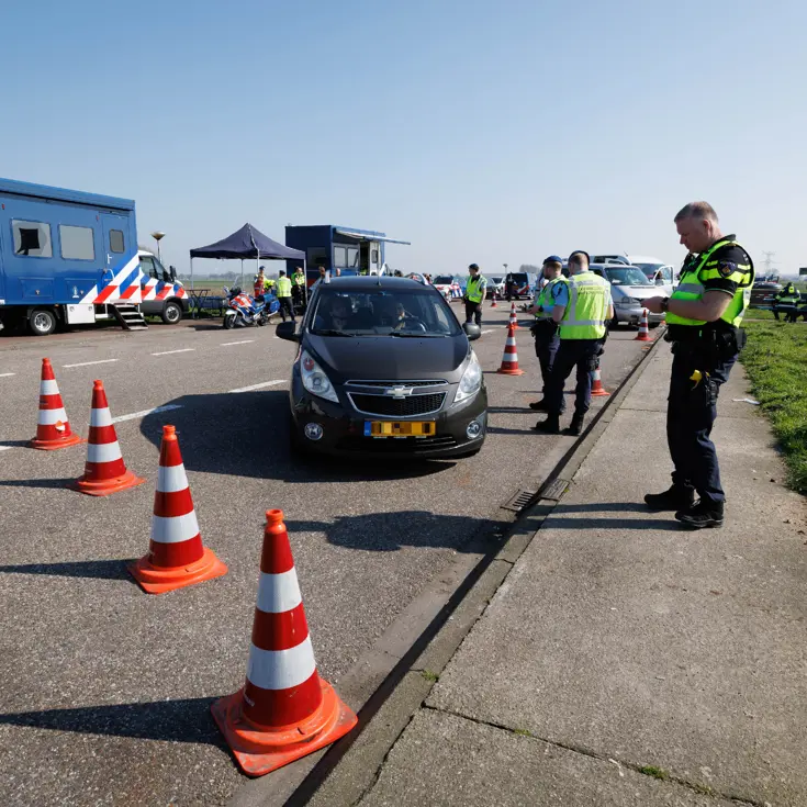 Politie en Marechaussee tijdens een controle op een parkeerplaats.