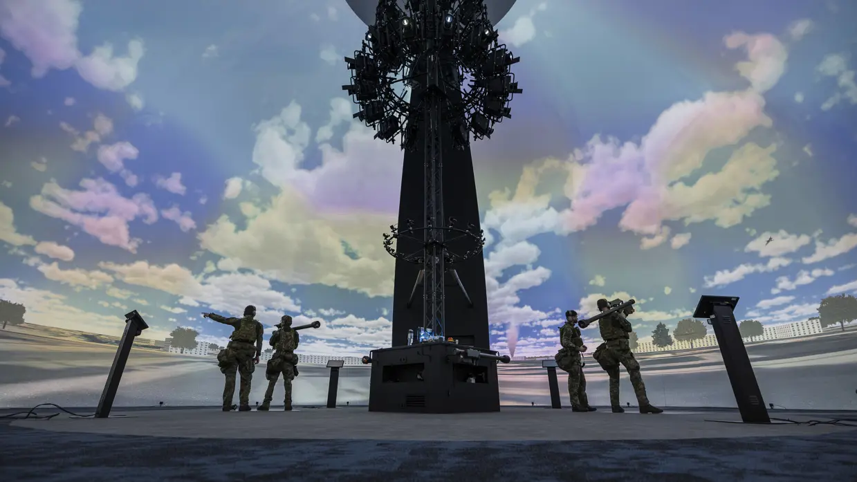 4 militairen staan in een grote, koepelvormige ruimte waar een wolkenlucht op de wand is geprojecteerd.