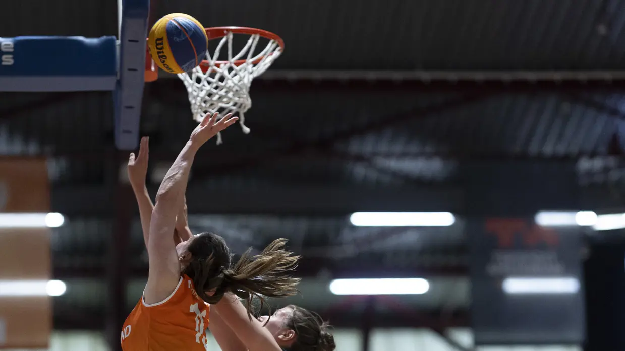 Een basketballer onder de basket in een sportzaal.