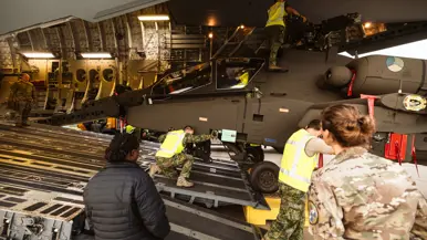 Majoor Saskia (rechts) kijkt hoe militairen in gele hesjes een Apache uit het laadruim duwen.