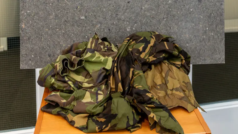 Militaire kleding ligt op een hoopje op een tafel.
