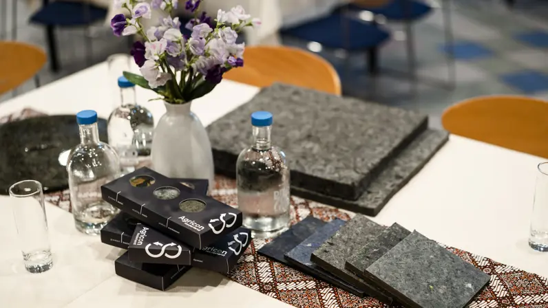 Concrete toepassingen van gerecycled textiel: op de tafel liggen wandpanelen en materiaalstalen die zijn ontwikkeld uit oude kleding, als onderdeel van de circulaire textielketen.