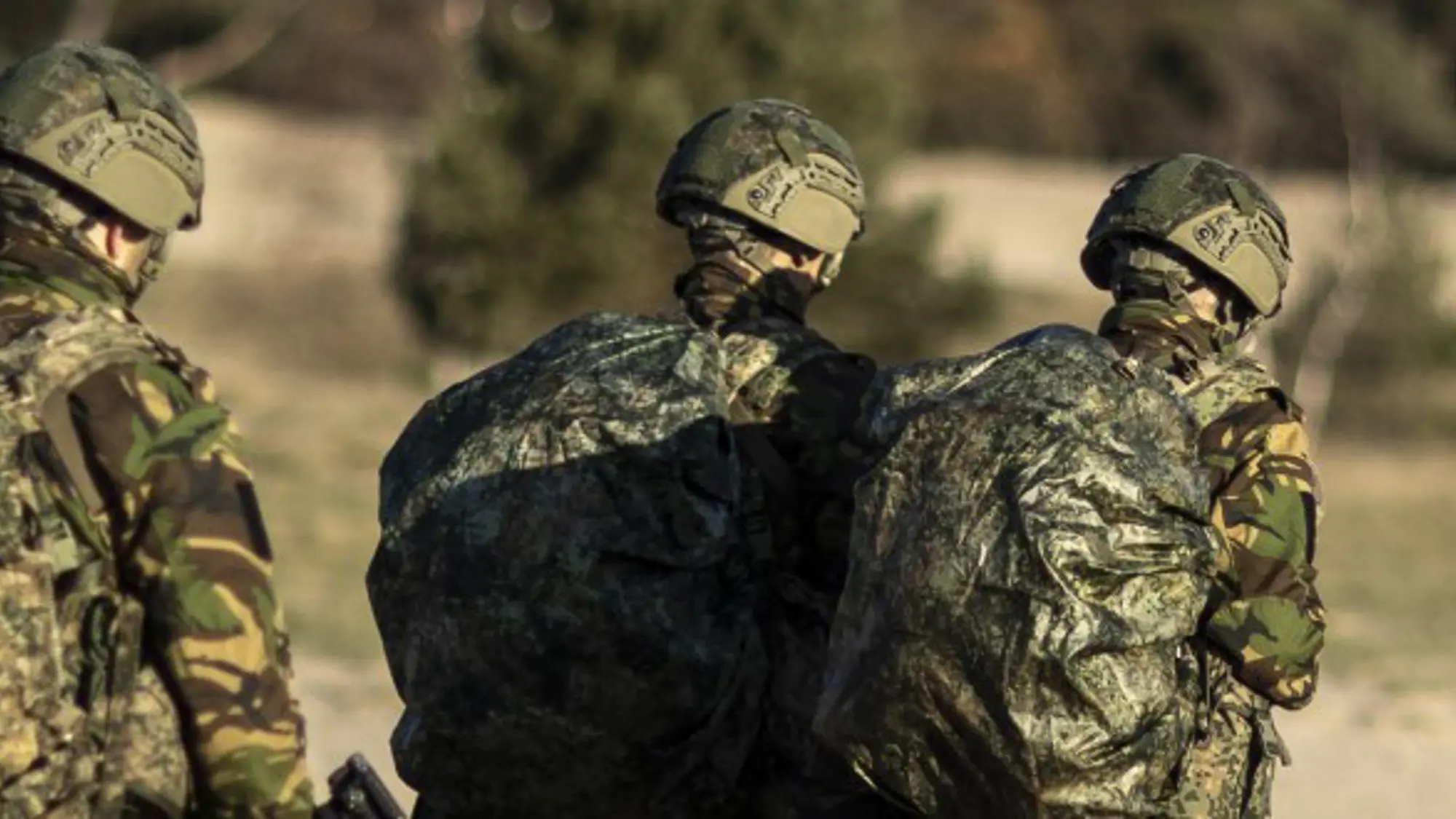Vijf militairen lopen met bepakking over de heide.
