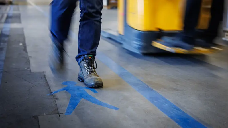 Een persoon met wandelschoenen beweegt zich langs een blauwe lijn. Daarnaast is een blauw poppetje afgebeeld, om aan te geven waar je mag lopen.
