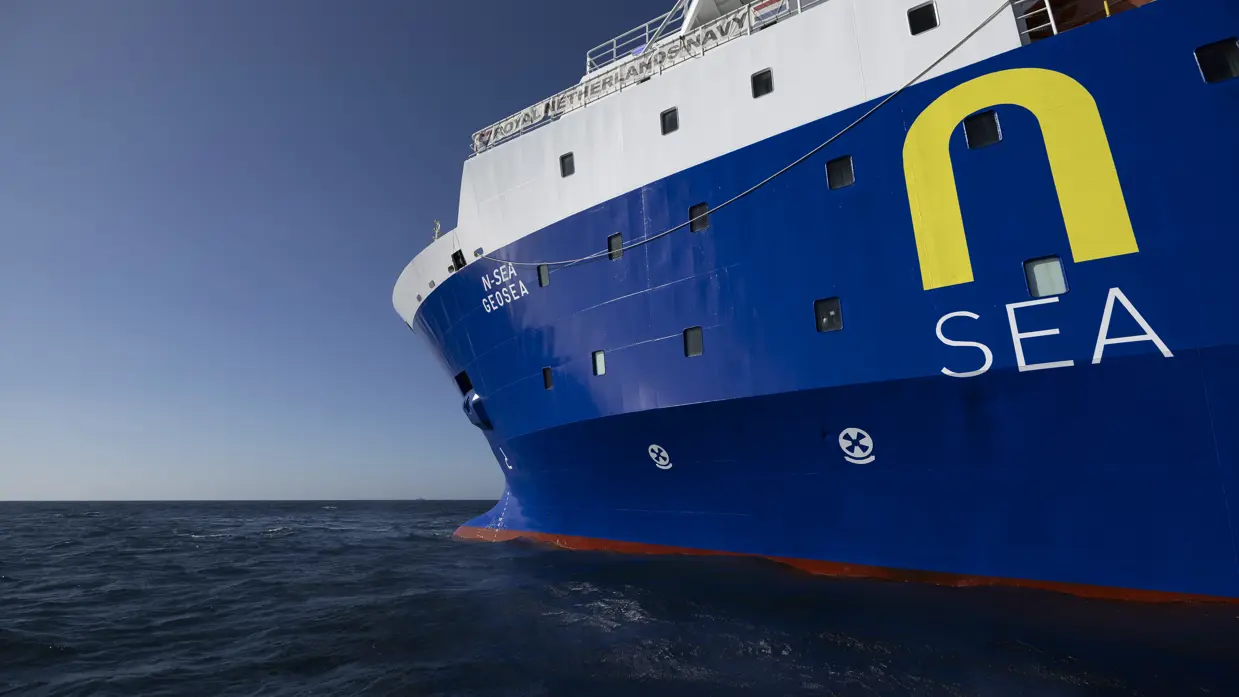 Een blauw-wit schip dobbert op zee. 
