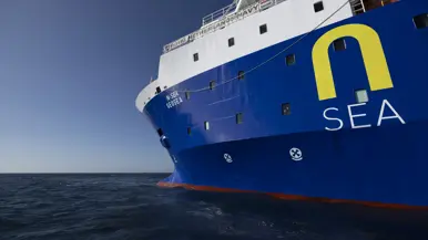 Een blauw-wit schip dobbert op zee. 