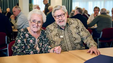 Een vrouw en een man lachen en zitten aan een tafel.