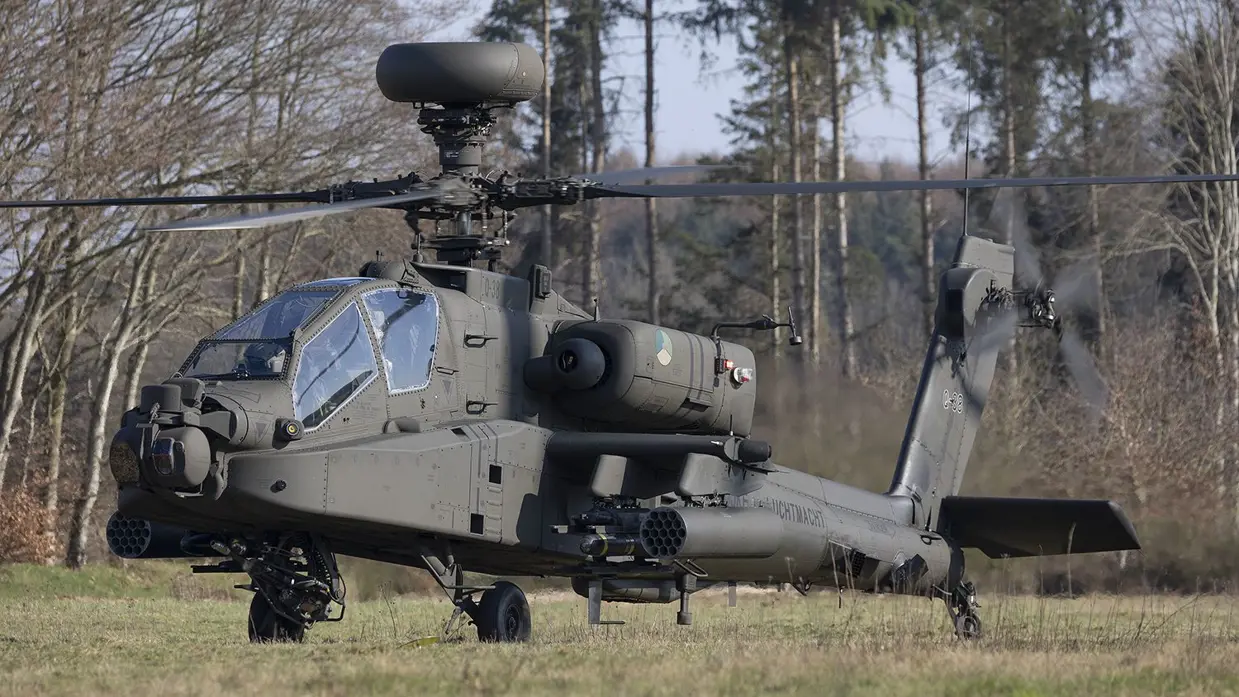 Een zwarte gevechtshelikopter met zware bewapening en draaiende rotorbladen staat op een grasveld tussen kale bomen in een bosrijke omgeving. Rechts: Een militaire helikopter vliegt laag boven een open veld, veroorzaakt stofwolken met ingeladen wapens en draaiende rotorbladen tussen kale bomen.