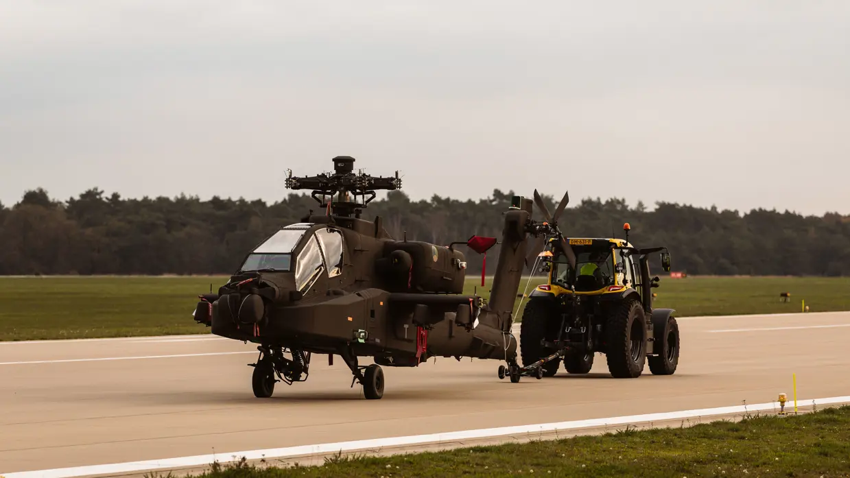 Een trekker sleep een Apache over de landingsbaan. De Apache heeft geen rotorbladen.