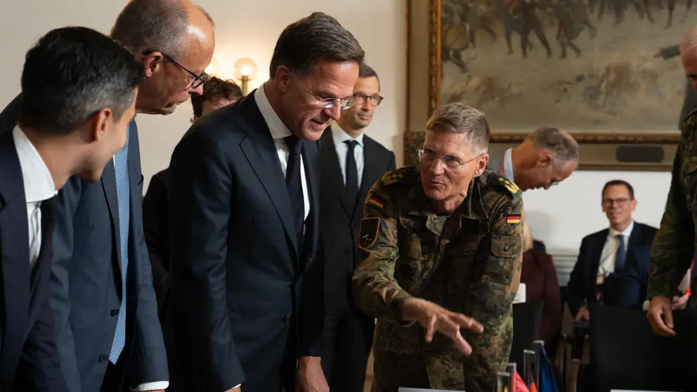 Drie politici in gesprek met militairen.