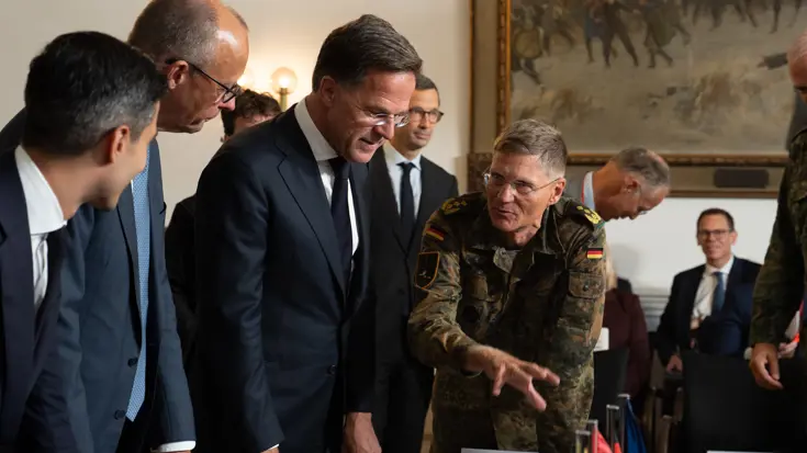 Drie politici in gesprek met militairen.