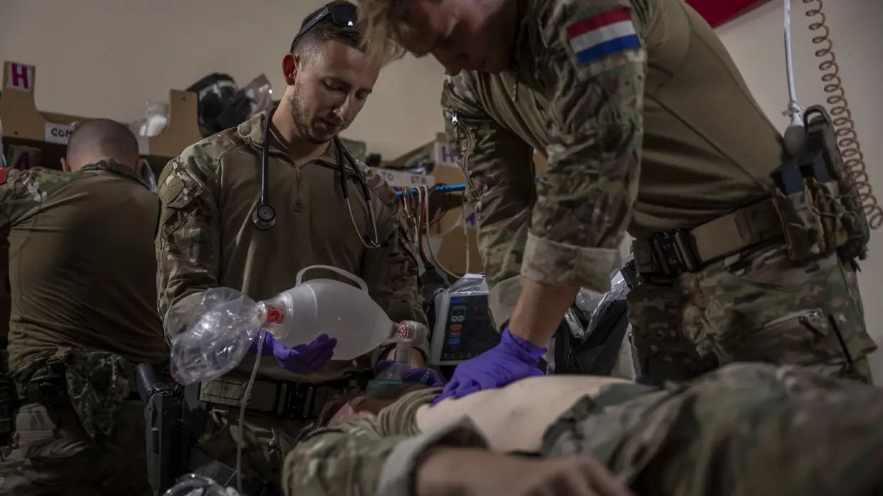 Een militair met een Nederlandse vlag op de schouder reanimeert een pop. Een collega geeft het gefingeerde slachtoffer zuurstof met een rubberen knijpzak.
