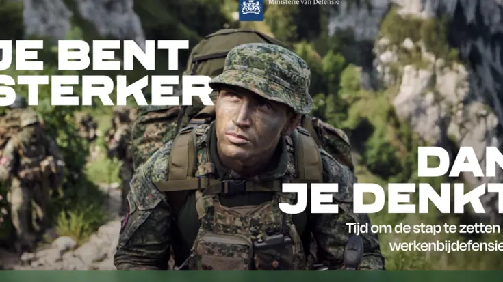 Militair in uniform met groengekleurd gezicht en een slap hoedje op. Op zijn rug een rugzak. Rotsige bergen op de achtergrond.