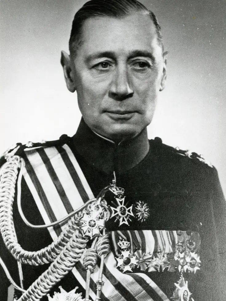 Zwart-wit portret van Generaal Ben Hasselman, chef van de Generale Staf, in donker uniform met hoge kraag en gevlochten koorden op de schouders. Op zijn borst pronken sterren en kruisen; waardige, officiële sfeer tegen een lichte achtergrond.