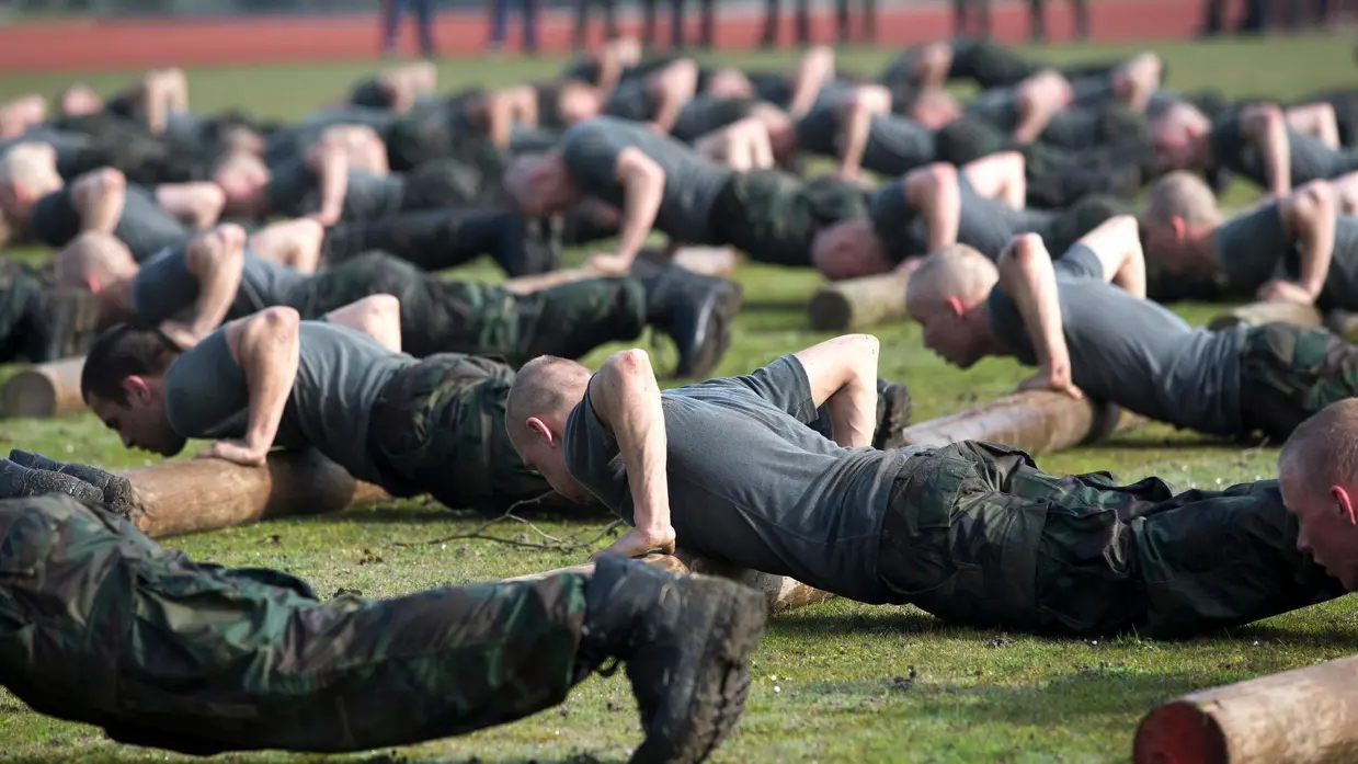 Groep militairen is aan het opdrukken in het gras.
