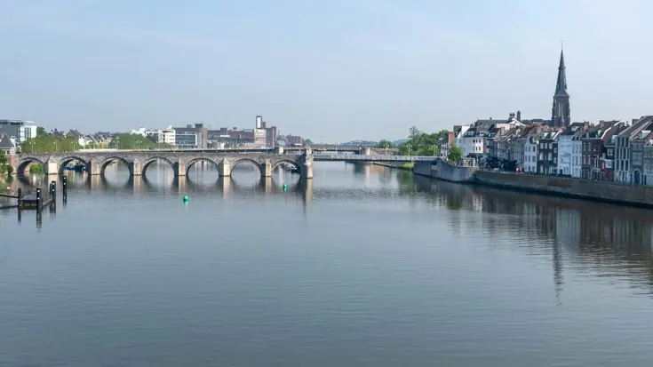 Rivier de Maas stroomt onder oude brug in Maastricht.