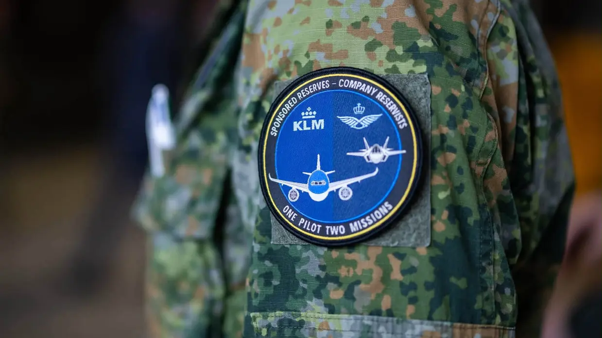 Een samenwerkings-badge van de luchtmacht en KLM op een mouw van een camouflagepak