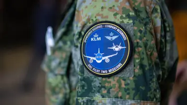 Een samenwerkings-badge van de luchtmacht en KLM op een mouw van een camouflagepak