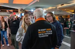 2 bezoekers luisteren naar een defensiemedewerker.