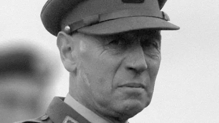 Zwart-wit portret van een militair in donker uniform en een pet op.