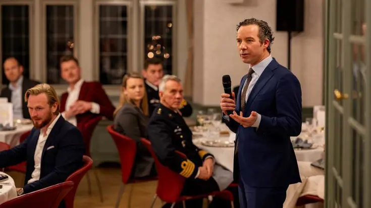 Een hoogleraar spreekt een zaal toe.