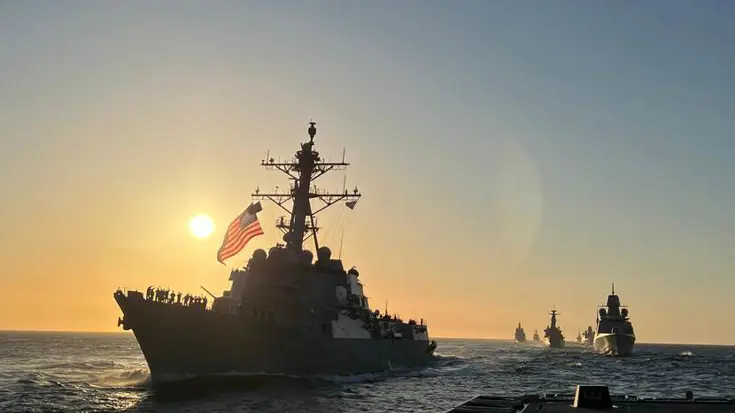 Marineschip op zee met ondergaande zon.
