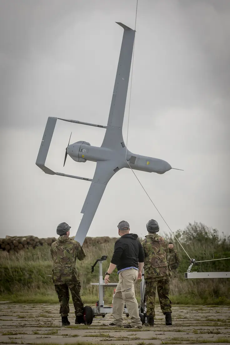 3 personen halen een onbemand toestel met een opvanginstallatie uit de lucht.