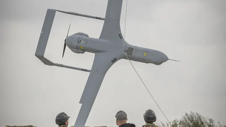 3 personen halen een onbemand toestel met een opvanginstallatie uit de lucht.